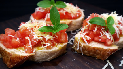Bruschetta with tomatoes basil and parmesan cheese. Tomatoes on toast close up selective focus.