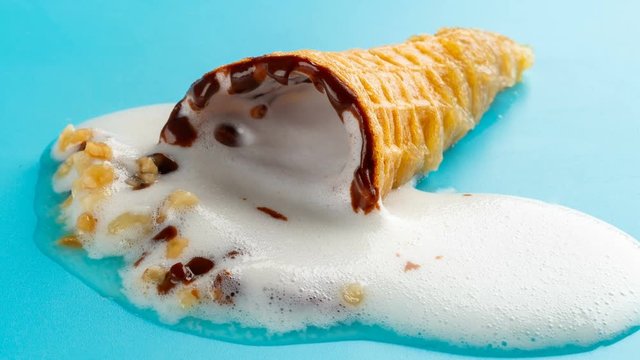 reverse studio shoot of mini white ice cream cone melting on blue time lapse