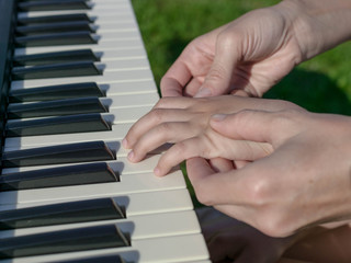 Obraz premium Mother teaches the daughter to play the piano. Concept Mother's Day. Female and children's hands.