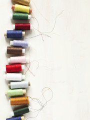 Colourful thread spools on a white wooden background with copy space