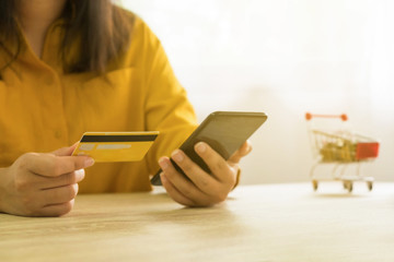 Woman holding credit card and using smartphone for shopping online.