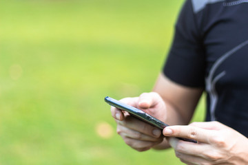 Man using mobile smartphone in park - focus on top of the phone with copy for text.