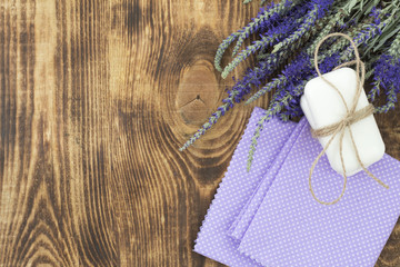 Natural soap, towels and flowers on old wooden table. Spa treatments, skin care concept. Soap making. Flat lay.