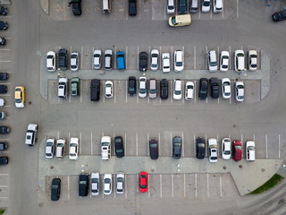 Aerial view of a large number of cars of different brands and colors standing in a parking lot near the shopping center in a chaotic manner. Parking divided by white dividing strips and sidewalks © Aleksandr Kondratov