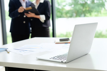 Desk with laptop, paper and business office background.