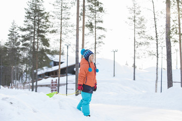 Fototapeta na wymiar 雪景色とソリで遊ぶ子供