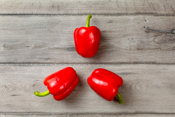 Table top photo - three bright red bell peppers arranged into 3 pointed star shape.