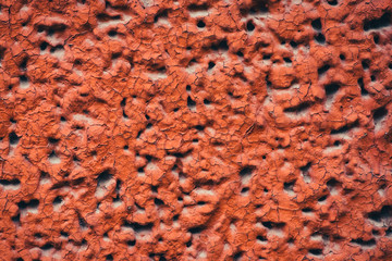 Side of building is painted red. Detailed imperfect texture of aerated foam block with holes close-up. Background of construction from foamed material in macro with copy space. Decorative facing.