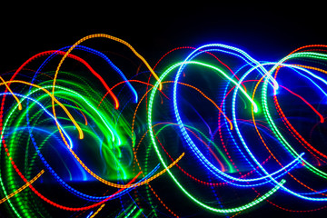 Blur colourful Abstract background of glowing stripes of streaks of light bands in a form of several lines on black background. Long exposure