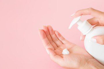 Young, perfect, groomed woman's hands using moisturizing, natural herbal cream. Care about clean, soft and smooth body skin. Copy space. Empty place for text or logo on pink background.