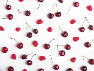 Ripe raspberries and cherries on the white background.