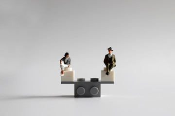 The concept of equality of opportunity for men and women. A miniature man and woman sitting on a...