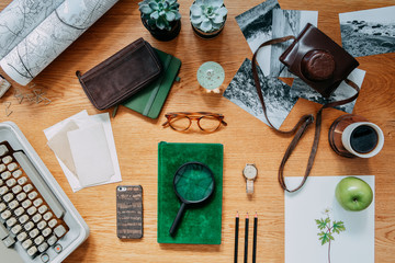 Modern composition of  wooden desk with typewiter, photos, notebook, retro camera , map and office accessories. Creative desk of traveler and adventure man. 