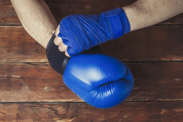 man's hand in boxing bandages and a boxing glove on a wooden background. The concept of training...