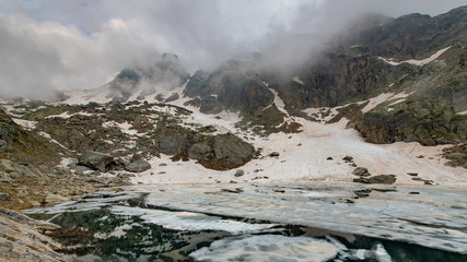 Small lake in thaw on Italian Alps in the middle of the mountains
