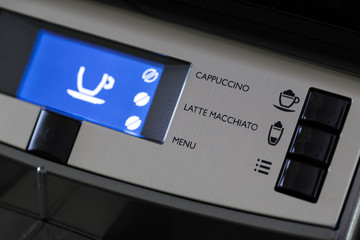 The panel of the automatic coffee machine with the inscriptions of drinks and the blue display