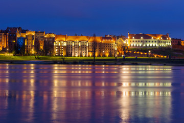 Granaries of Grudziadz at night reflected in Wisla river, Poland. Europe.
