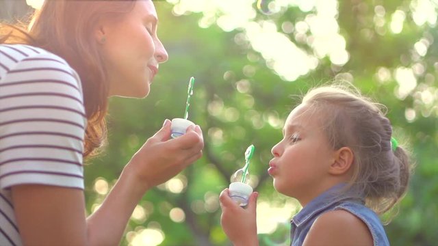 Beautiful mother and her little daughter having fun in summer park together. Slow motion 4K UHD video 3840X2160