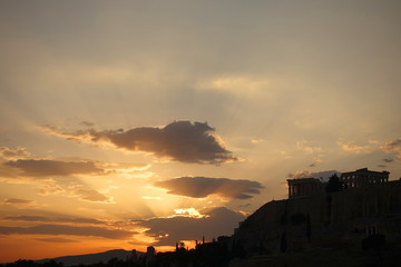 Fototapeta premium Iconic Acropolis hill and the Parthenon as seen from rooftop at sunset with golden colours and beautiful cloud formations, Athens historic center, Attica, Greece 