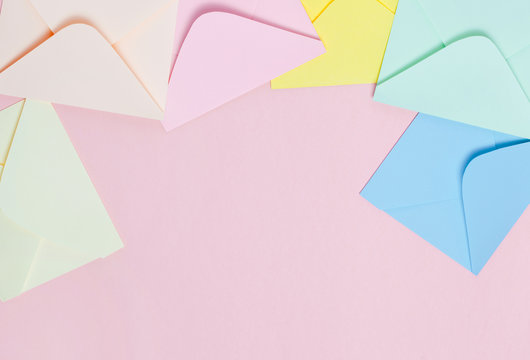 Frame from colorful envelopes on pink table top view.