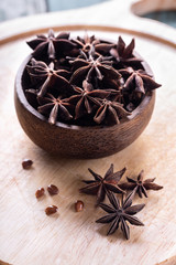 Whole star anise in wooden bowl on cutting board