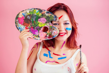 Fototapeta premium dirty visagiste ( make-up artist ) stains from paint on the face palette in hands on a pink background in studio