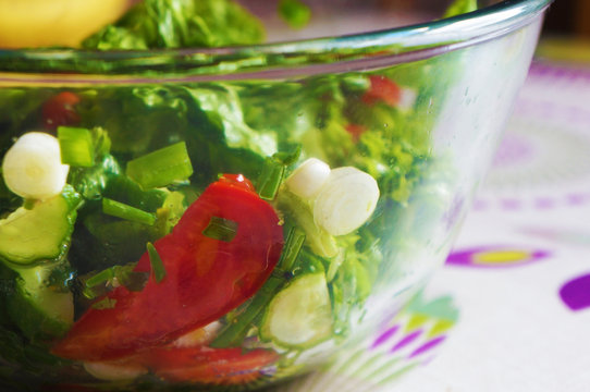 Salad with tomatoes, cucumbers, lettuce and green onions in bowl. Closeup side view.