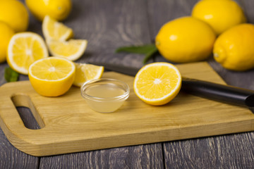 Pieces of lemon and knife on cutting Board, juice in bowl