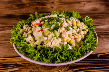 Ceramic plate with salad from crab sticks on wooden table