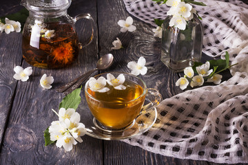 Herbal tea in teapot and Cup, Jasmine flowers scattered on wooden table