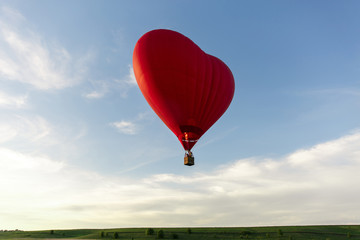 Red hot air balloon in the shape of a heart fly in sky. Love, honeymoon and romantic travel concept