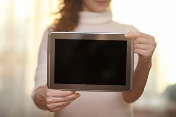 The girl is holding a tablet. The girl has a computer with a scr