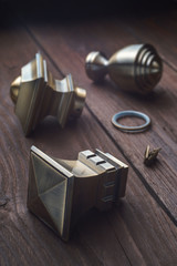 The tips for curtain rails lie on an old wooden table. The metal tips for the cornices lie on an old dark wooden table.