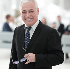closeup of a serious senior businessman with glasses in hand.