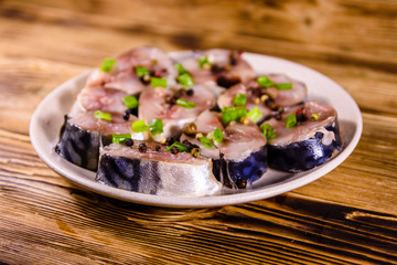 Sliced scomber fish with green onion on a ceramic plate on wooden table