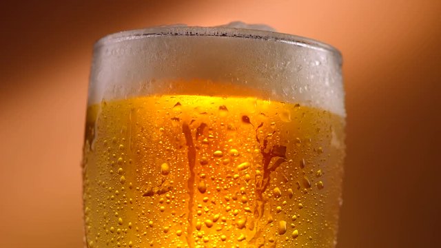 Cold beer in a glass with water drops. Craft beer close up. Rotation 360 degrees. 4K UHD video 3840x2160