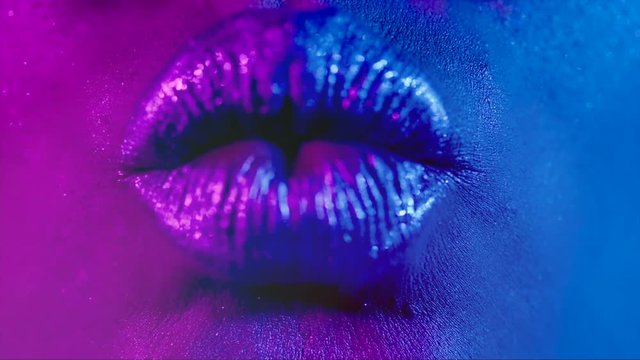 Lips kiss in bright neon UV lights. Beauty sexy model lips close-up. Slow motion 4K UHD video 3840X2160