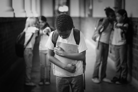 Sad pupil being bullied by classmates at corridor