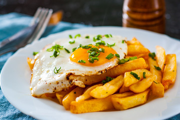 fried egg with potato in a white plate on table
