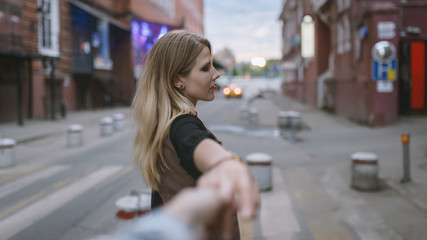 Follow Me - young woman pulls the mens hand on the street at sunset.