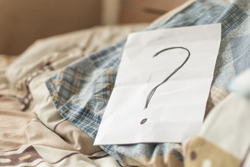A question mark on paper on the bed.