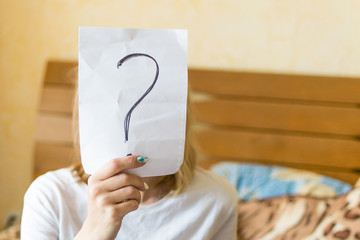 An anonymous woman holds a question mark.