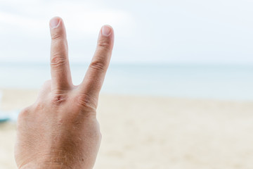 Gesture Ok on the background of the beach. Raised top of the thumb of a male hand.