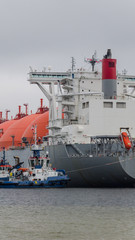 LNG TANKER - A large ship at the gas terminal is secured by tugs