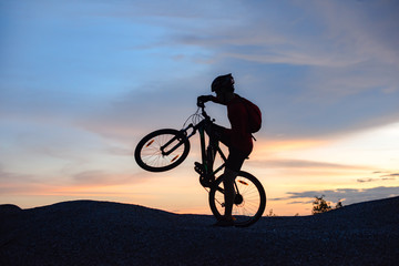 Fototapeta na wymiar silhouette of a man riding a mountain bike up a hill, extreme sport mountain biker