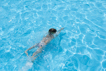 healthy little boy diving in azure swimming pool in sunny summer day resort