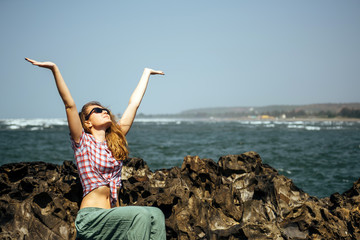 Beautiful girl relaxing on sea rocks