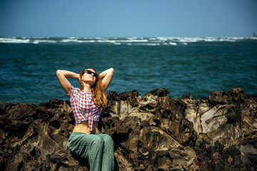 Beautiful girl relaxing on sea rocks