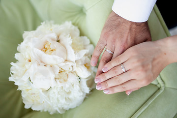 Obraz na płótnie Canvas Bridal bouquet of white peonies and hands with wedding rings
