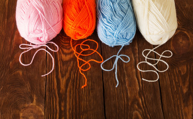 Skeins of yarn of different colors lie on wooden table